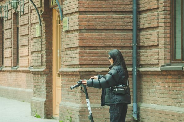 Woman with electric scooter on European cobblestone street