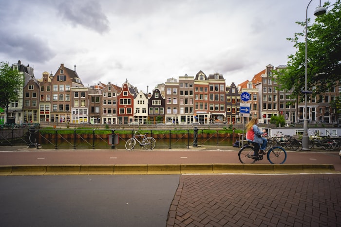 Cyclist passing traditional Dutch houses on a canal street